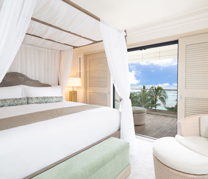 Room with a canopy bed, lap, seating area, and balcony.